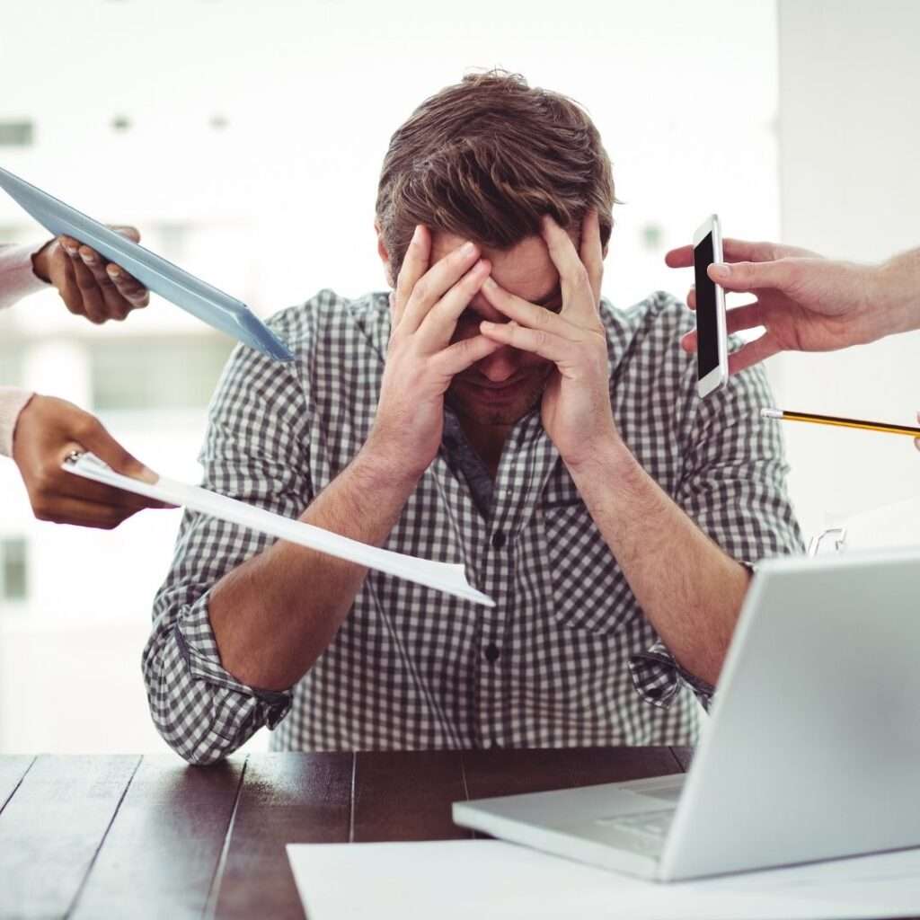Man with head in hands surrounded by papers and devices, illustrating stress during ERP change management.