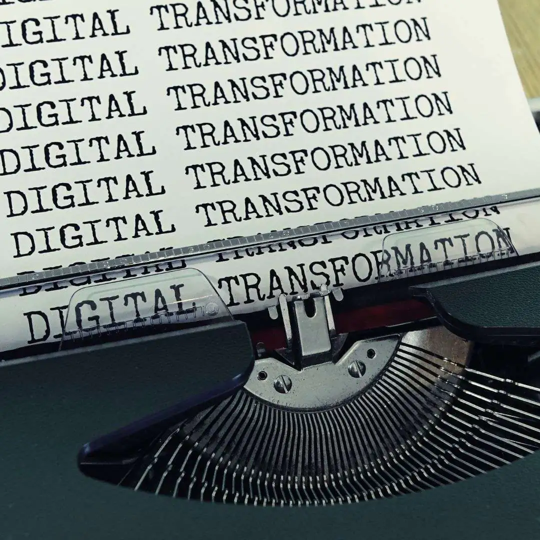 Typewriter with repeated text "DIGITAL TRANSFORMATION" illustrating themes of change management and organizational transformation.