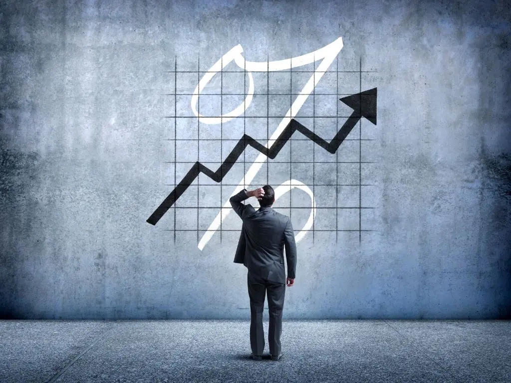 Business professional observing a rising graph on a wall, symbolizing change management and organizational growth.