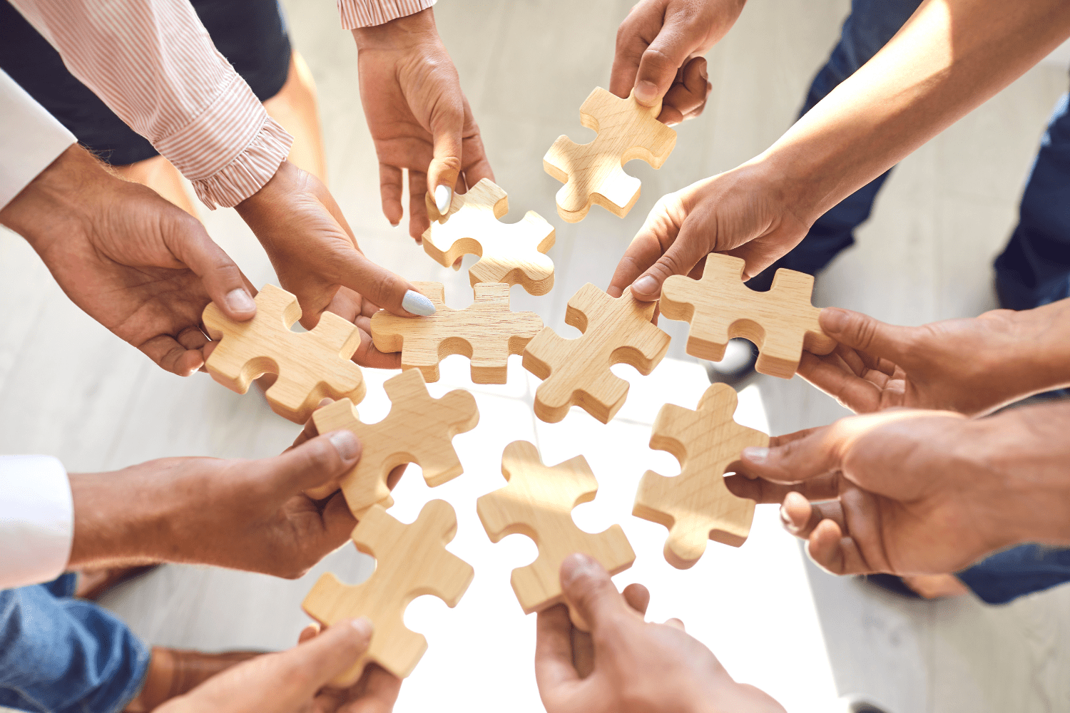 Hands holding wooden puzzle pieces, collaborating on change management strategies in a team setting.