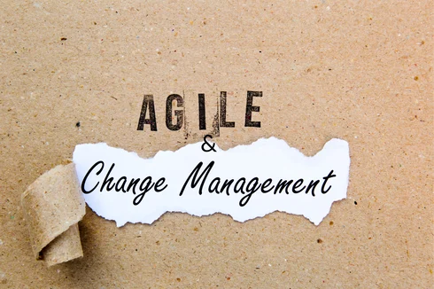 Text on torn paper reading "AGILE & Change Management" on a textured background, emphasizing change management methodologies.