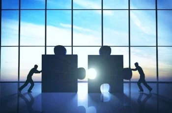 Two silhouettes pushing large puzzle pieces together in front of a large window, symbolizing organizational change and collaboration.